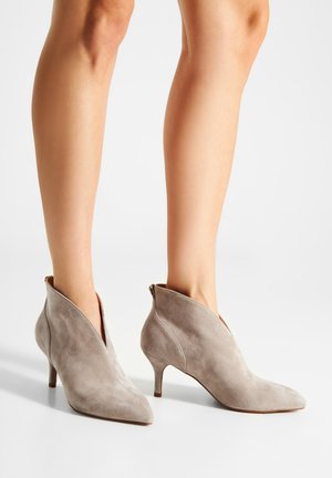 Stivaletti alla caviglia in suede grigio con punta affusolata e tacco a stiletto basso, caratterizzati da un design a taglio unico alla caviglia che aggiunge interesse.