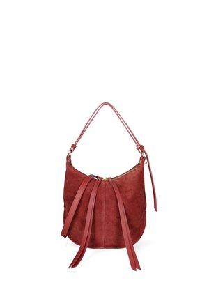 Sac à épaule en daim rouge avec des bretelles ajustables, une fermeture éclair et des pompons en cuir décoratifs suspendus à l'avant.