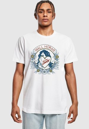 Hvid bomulds t-shirt med et farverigt trykt design, der viser en kvinde, der holder et hjerte, omgivet af blomsterlige elementer og tekst.