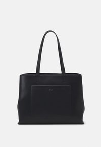 Zwarte leren tote bag met twee lange hengsels, een voorvak met patch, en geëtst logo-detail. Gladde textuur en minimalistische uitstraling.