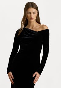 Černé sametové šaty s dlouhými rukávy, designem bez ramínek, hladkou texturou a přiléhavým siluetou, která ukazuje elegantní detaily splývání.