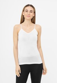 Haut débardeur blanc sans manches avec fines bretelles, coupe ajustée et encolure en V, fabriqué en tissu léger et extensible.