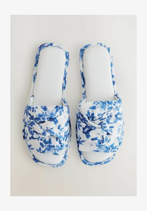 Sandaalit, joissa on kukkakuviot valkoisena ja sinisenä sekä solmittu muotoilu; pehmeä kankainen päällinen ja teksturoitu pohja mukavuutta varten.