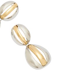 Dekoracyjny element w tonacji srebra i złota, zawierający owalne kształty o wypolerowanych powierzchniach, podkreślający kontrastowe kolory i zakrzywione wzory.