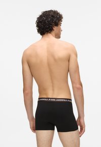 Černé boxerky s kontrastním lemem a logem "KARL LAGERFELD"; látka je hladká a střih je těsně přiléhavý a moderní.