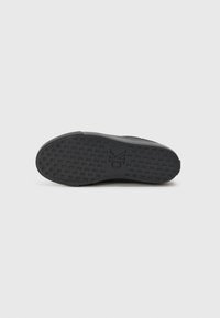 Fekete sneaker talp, textúrált tapadó mintázattal, látható logóval és kerekített formával. Gumi anyagból készült, sima felülettel.