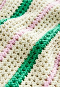 Gros plan sur un tissu crocheté texturé avec une base crème et des rayures alternées roses et vertes.