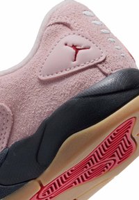 Baskets en daim rose avec une semelle intermédiaire noire, une semelle en caoutchouc avec des accents rouges et une finition texturée. Comprend un détail de logo sur le côté.