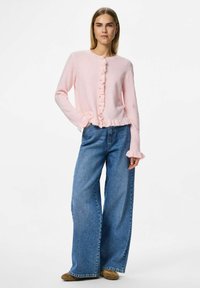 Pink wool-blend cardigan with ruffled front and cuffs, button closure, paired with wide-leg blue denim jeans and brown footwear.