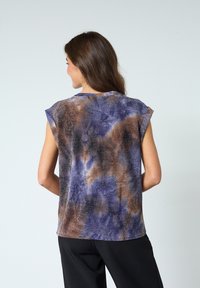 Kortärmad topp i batikmönster med blå, bruna och metalliska inslag; slät tyg med avslappnad passform.
