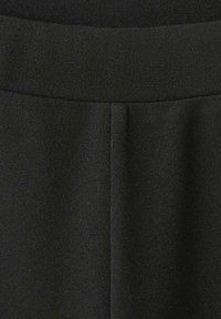 Haină din material textil negru cu o bandă elastică largă în talie. Textura pare netedă, cu ușoară elasticitate. Prezintă un tiv pliat în talie.