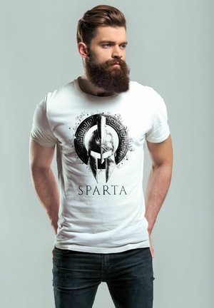 Weißes T-Shirt mit einem schwarzen Spartanerhelm-Graphic und dem Text "SPARTA" darunter. Das Model trägt dunkle Jeans und hat einen Bart.