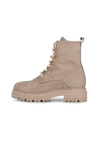 Bottines en suédine beige avec une semelle épaisse, un laçage à l'avant et des œillets métalliques dorés. Dotées d'une languette à l'arrière pour un enfilage facile.