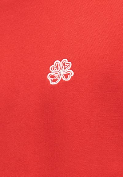 Κόκκινο ύφασμα με μικρό λευκό κεντητό σχέδιο τετράφυλλου τριφυλλιού στο κέντρο, με στυλιζαρισμένες γραμμές και στρογγυλεμένα σχήματα φύλλων.