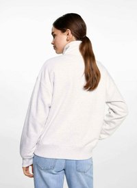 Lichtgrijze sweatshirt met hoge kraag, dropped shoulders en ribgebreide manchetten. De stof lijkt zacht met een ontspannen pasvorm en een eenvoudig ontwerp.