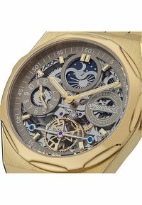 Goldfarbener Automatikuhr mit transparentem Skelettziffernblatt, das komplexe Zahnräder, einen Mondphasenanzeiger und zwei Hilfszifferblätter offenbart.