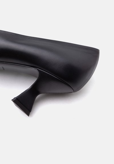 Μαύρη δερμάτινη γόβα με τετράγωνη μύτη και καλλιτεχνικά διαμορφωμένο μέτριο τακούνι σε λευκό φόντο.