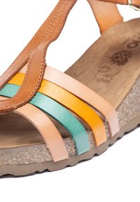 Sandale en cuir marron avec des brides multicolores en pêche, orange et bleu-vert. Elle présente une semelle beige texturée et une semelle intérieure rembourrée.