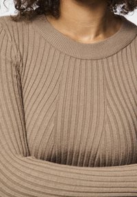 Pull à manches longues côtelé de couleur marron neutre, doté d'un col rond et d'un tissu texturé avec des rayures verticales.