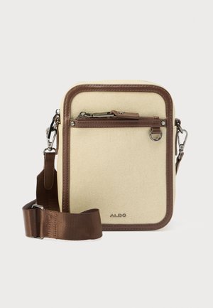 Kleine beige canvas crossbodytas met bruine bies, voorzak met rits, metalen ringdetail en verstelbare bruine riem.