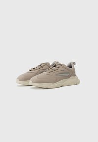 Beige sports shoes with a smooth suede upper, rounded shape, textured rubber outsole, and accent near the laces in a lighter shade.