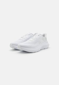 Baskets de sport blanches avec une tige en maille texturée, fermeture à lacets, col rembourré et semelle épaisse et amortie pour le soutien et le confort.