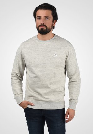 Sudadera gris de textura con cuello redondo, puños y bajo acanalados. Presenta un pequeño logo triangular en el lado izquierdo del pecho.