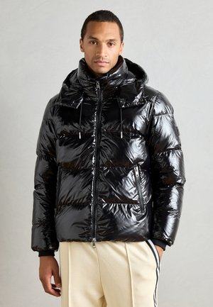 Black puffer jacket with a glossy finish, featuring a large hood, zippered pockets, and drawstring accents. Thick, quilted design for warmth.