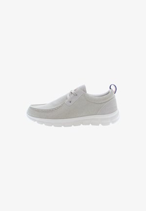 Ljusgrå slip-on skor med ett mjukt tygöverdrag, vit sula och subtila sömmar. Har en liten röd och blå accent på hälen.