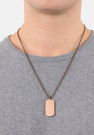 Collana in bronzo con un pendente rettangolare e liscio; il pendente è di un rosa chiaro e presenta bordi arrotondati, indossato sopra un maglione grigio.
