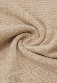 Tessuto a maglia beige con una sottile consistenza scintillante, caratterizzato da una finitura morbida e liscia e da un'aranziamento a spirale per un aspetto accogliente.