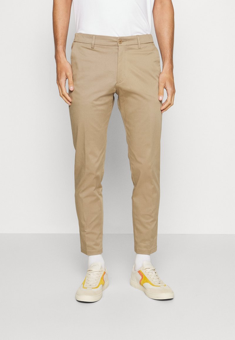 Beige chinos met een rechte snit, gemaakt van lichtgewicht stof, met voorzakken, een ritssluiting en een enkele knoopsluiting.