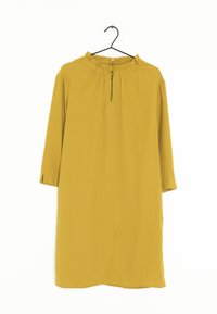 Senapsgul klänning med rund halsringning, halvlånga ärmar och en centralt placerad dragkedja. Släta tyg och en avslappnad passform.