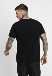 Svart bomulls t-skjorte med korte ermer, rund hals og en avslappet passform. Bakdelen har en jevn tekstur og et enkelt design.