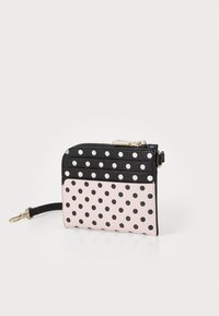 Portefeuille à pois noir et rose, avec une fermeture zippée, un matériau texturé et une bandoulière. Partie supérieure noire avec de grands pois blancs, partie inférieure rose.