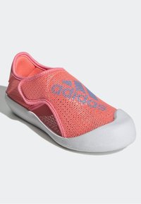 Scarpa slip-on in mesh rosa con suola in gomma bianca. Presenta una punta arrotondata e tagli laterali, con un logo blu nella parte superiore.