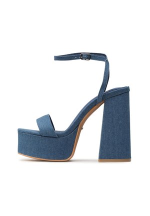 Sandalia plataforma de mezclilla azul con tacón alto, correa al tobillo con hebilla, tacón grueso y punta abierta, vista lateral sobre fondo blanco.