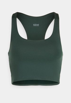 Tamsiai žalia sportinė liemenėlė su lenktais pečiais, pagaminta iš lygios, elastingos medžiagos. Yra be siūlių apatinis kraštas ir subtilus logotipas ant kaklo.