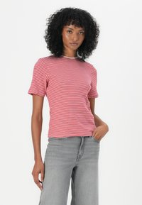 Tricou cu mânecă scurtă, alb și roșu în dungi, cu decolteu rotund, design ajustat și textură netedă. Purta cu blugi gri cu picior larg.