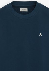 Mørkeblå crewneck-sweatshirt med lille hvidt kranie- og ben kors-logo på brystet og Scalpers-mærke inde i kraven.