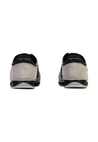 Scarpe in suede grigio con accenti neri, forma arrotondata e design testurizzato. Presentano una suola liscia con un leggero tacco e un dettaglio del logo.