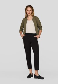 Olive green quilted jacket, white top, black tapered pants, black loafers. Simple design with pockets and elastic waistband on pants.