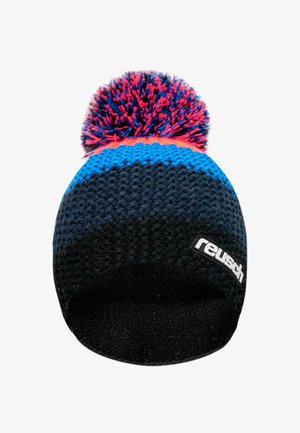 Knit beanie in blue, black, and red with a textured pattern, topped with a fluffy pom-pom. Features a branded black label on the side.