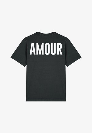 Melna kokvilnas t-krekls ar vārdu "AMOUR", kas drukāts treknajos baltajos lielajos burtiem uz muguras. Īsas piedurknes un apļveida kakla dizains.
