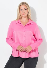 Lyserød satin langærmet skjorte med knaplukning foran, krave, buet kant og en glat struktur. Båret med mørkegrå bukser.