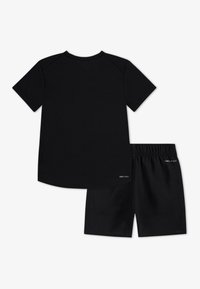 Conjunto desportivo DRI-FIT preto, composto por uma t-shirt de manga curta e calções. Feito de um tecido suave com uma cintura elástica nos calções.