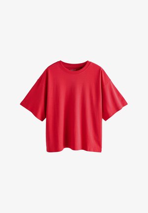 Punainen lyhythihainen t-paita, joka on valmistettu puuvillasta. Se on väljät yksi koko, ja siinä on pyöreä kaula-aukko. Pintakuviointi on sileä ilman näkyviä kuvioita tai koristeita.