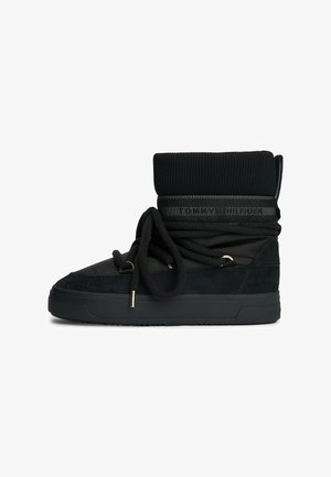 Sneaker nera a metà altezza realizzata in suede e tessuto, con un bordo rigato e lacci spessi, dettagli in oro e suola in gomma piatta.