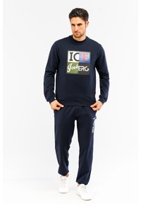 Marineblaue Sweatshirt und passende Jogginghosen aus weichem Stoff. Mit grafischem Druck in mehreren Farben auf der Brust und seitlichem Textdetail.