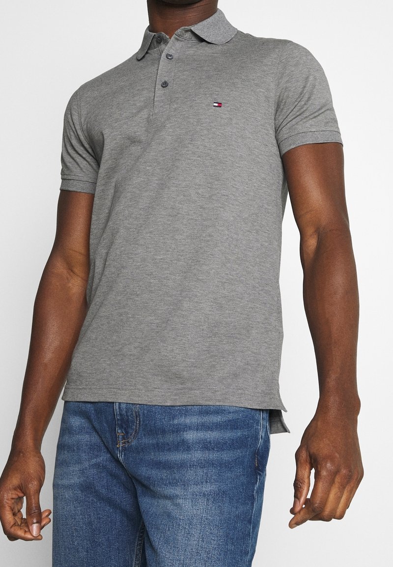 Grå polo t-shirt i bomullsmix, med klassisk krage, korta ärmar och en logodetalj på bröstet. Slim fit-design.